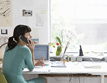 Young,Female,Artist,Using,Cell,Phone,At,Desk